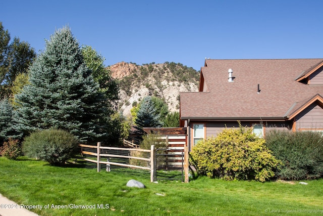 view of side of home with a mountain view and a yard