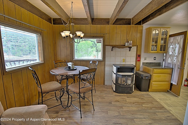 dining room with beamed ceiling, a chandelier, and wooden walls