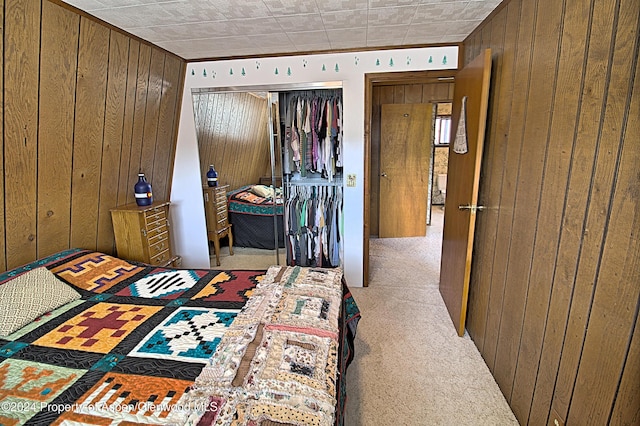 bedroom featuring light carpet, a closet, and wood walls