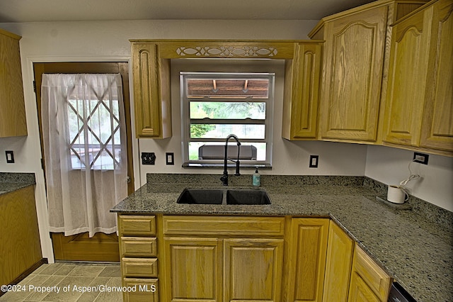 kitchen with stone counters, sink, and a healthy amount of sunlight