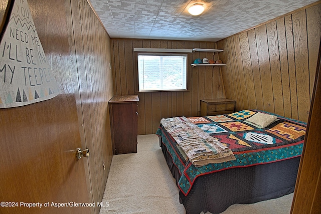 bedroom with light carpet and wooden walls