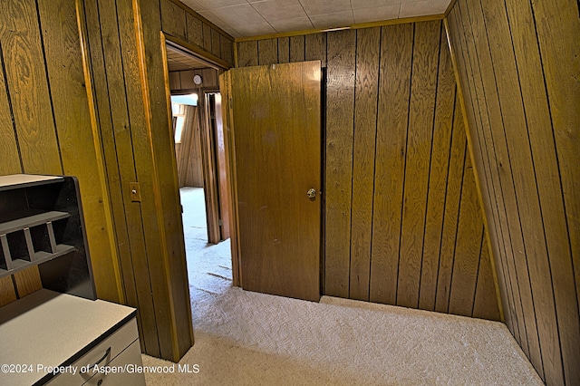 hallway featuring wood walls and light colored carpet