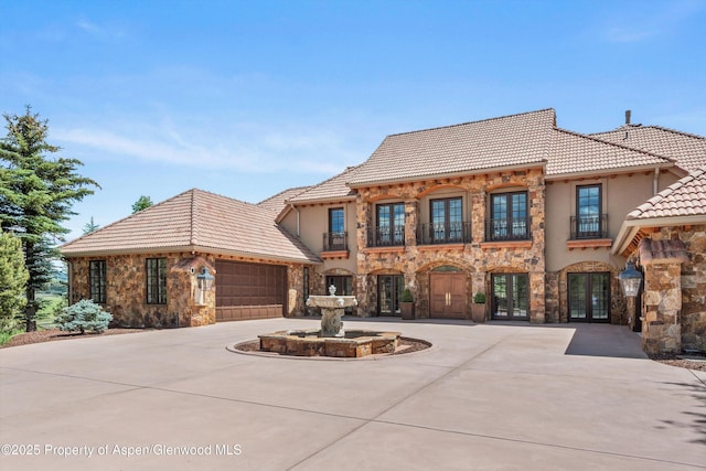 2959 County Road 103, Carbondale, CO 81623 - view of front facade featuring french doors, stone siding, a tile roof, curved driveway, and a balcony
