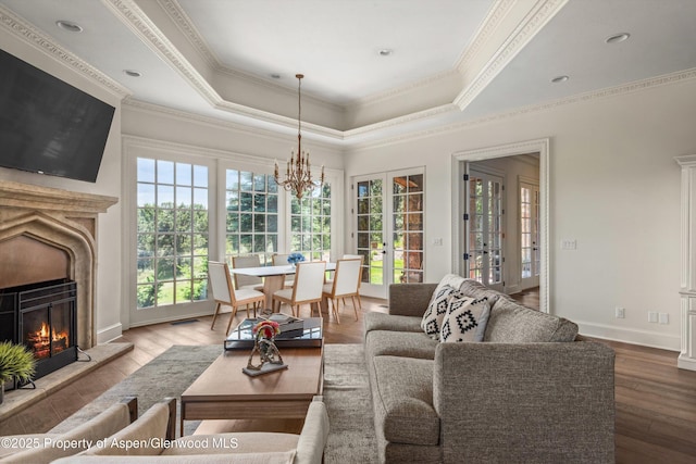 2959 County Road 103, Carbondale, CO 81623 - living room with a warm lit fireplace, wood finished floors, a tray ceiling, a chandelier, and crown molding