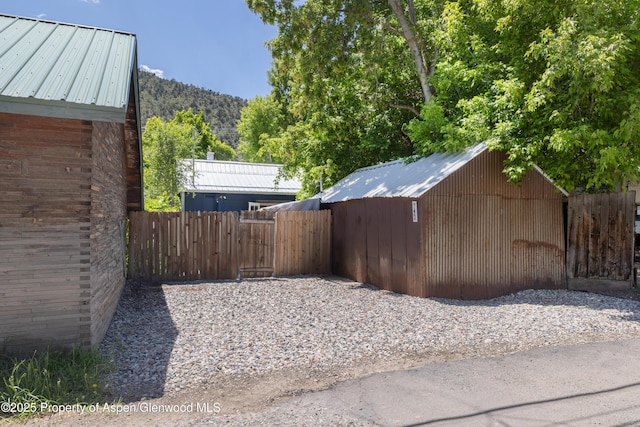 742 W Main St, New Castle, CO 81647 - view of home's exterior with metal roof, a gate, a mountain view, and an outbuilding