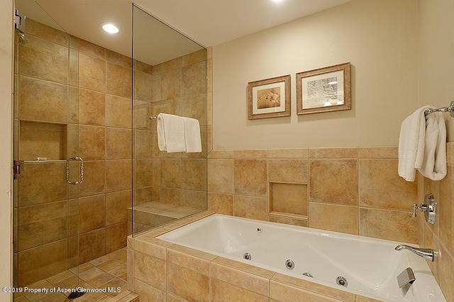 full bathroom featuring a whirlpool tub and a shower stall