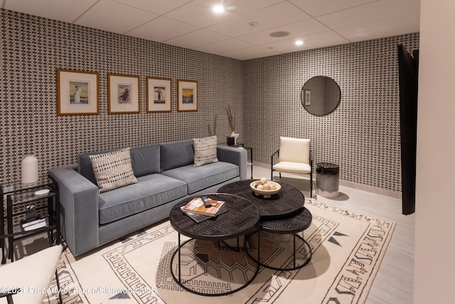 living room featuring a paneled ceiling and wallpapered walls