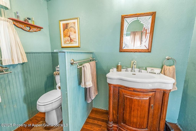 bathroom featuring wainscoting, vanity, toilet, and wood finished floors