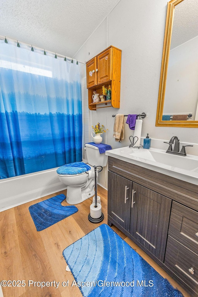 full bath featuring toilet, wood finished floors, and a textured ceiling