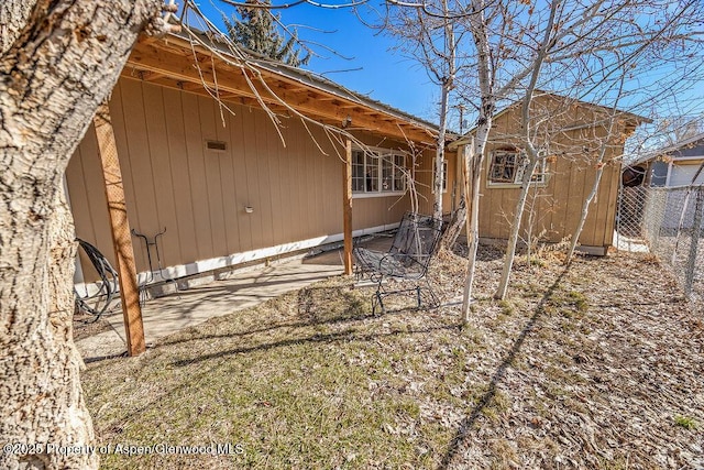 rear view of house featuring an outbuilding and fence