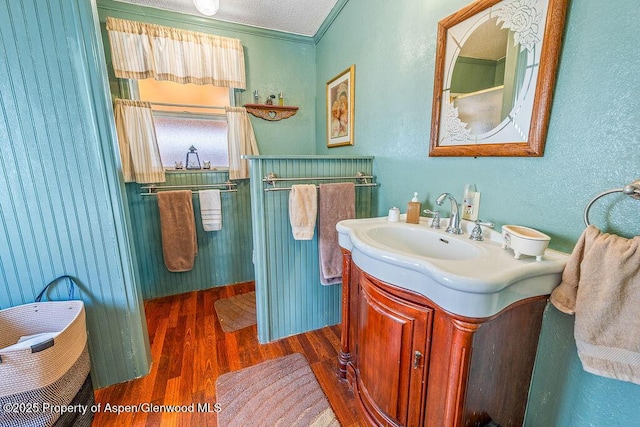 bathroom with vanity, crown molding, a textured wall, and wood finished floors