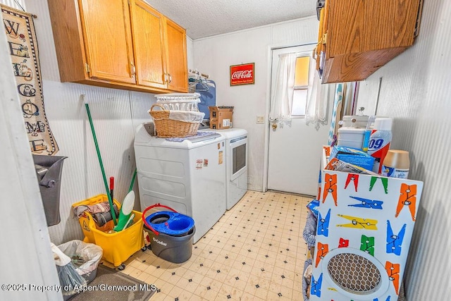 clothes washing area with cabinet space, light floors, washing machine and dryer, and a textured ceiling