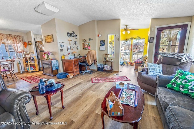 living area with a healthy amount of sunlight, lofted ceiling, a ceiling fan, and wood finished floors