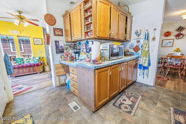 kitchen with visible vents, stainless steel microwave, brown cabinets, a ceiling fan, and open shelves