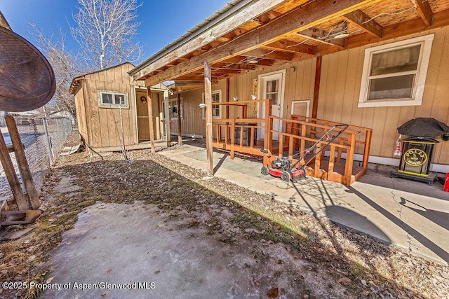 view of patio with a storage unit, an outbuilding, and fence