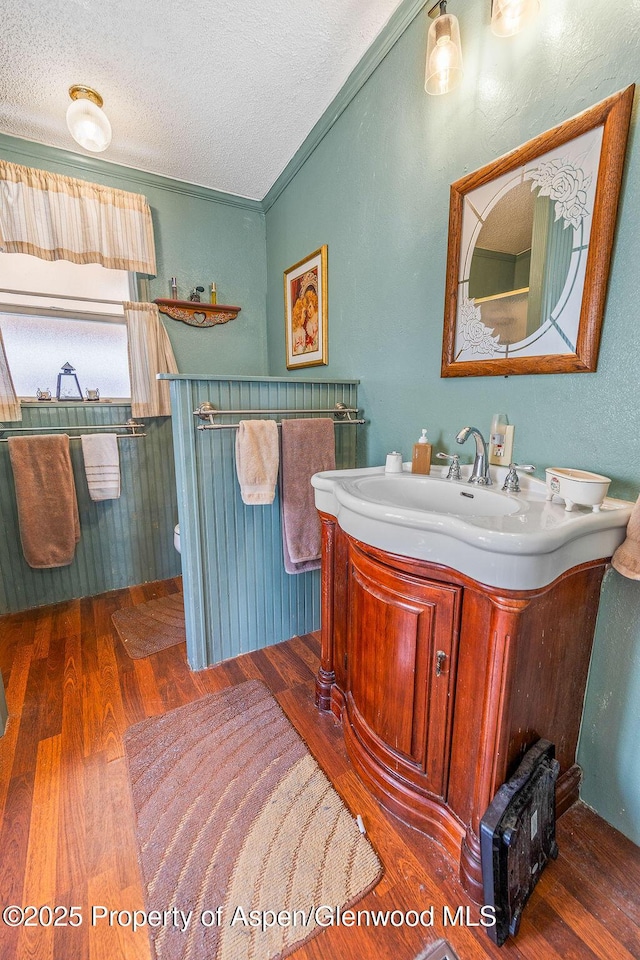 bathroom with vanity, crown molding, wood finished floors, and a textured ceiling