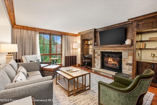 living room featuring light wood-type flooring, a stone fireplace, and ornamental molding