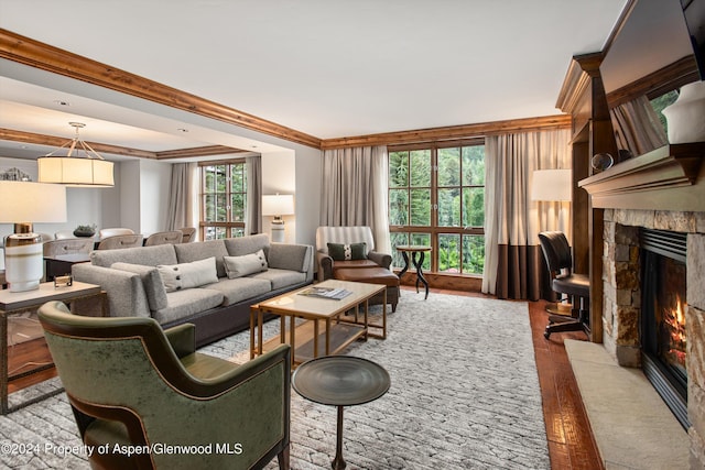 living room with crown molding, a wealth of natural light, a fireplace, and hardwood / wood-style floors