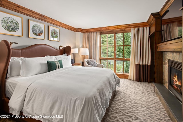 bedroom with a tile fireplace, crown molding, and carpet floors