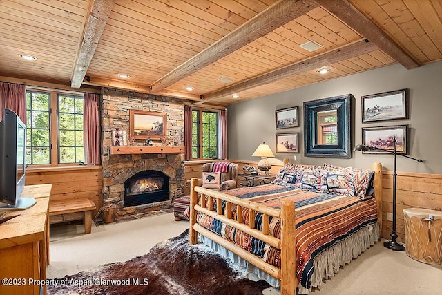 bedroom featuring beam ceiling, a stone fireplace, wooden walls, carpet, and wood ceiling