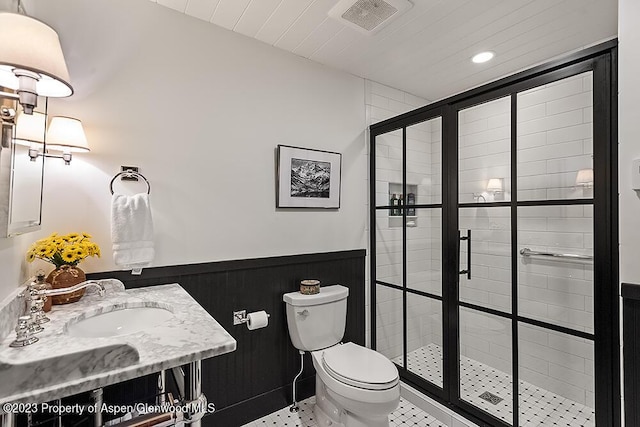 bathroom with sink, a shower with shower door, and toilet