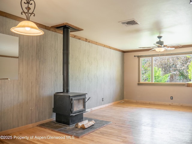 783 Orchard Rd, Montrose, CO 81401 - unfurnished living room with a ceiling fan, wood finished floors, a wood stove, and baseboards
