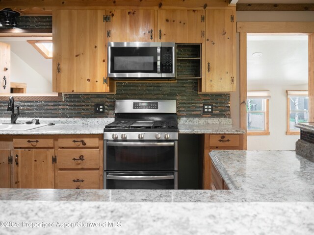 783 Orchard Rd, Montrose, CO 81401 - kitchen with stainless steel appliances, a sink, decorative backsplash, and light stone counters