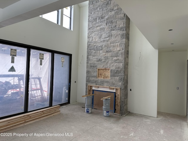 unfurnished living room with a towering ceiling and a fireplace