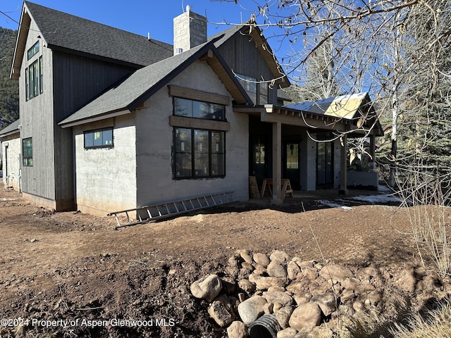 exterior space featuring a shingled roof and a chimney