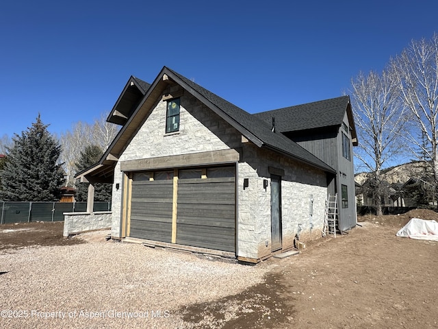 garage featuring driveway and fence