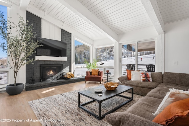 living room with a fireplace, wood-type flooring, lofted ceiling with beams, and wooden ceiling