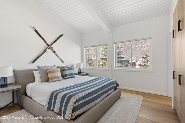 bedroom featuring light wood-type flooring, lofted ceiling with beams, and wooden ceiling