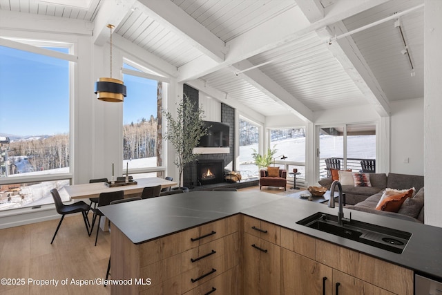 kitchen with rail lighting, a large fireplace, beamed ceiling, and hardwood / wood-style flooring