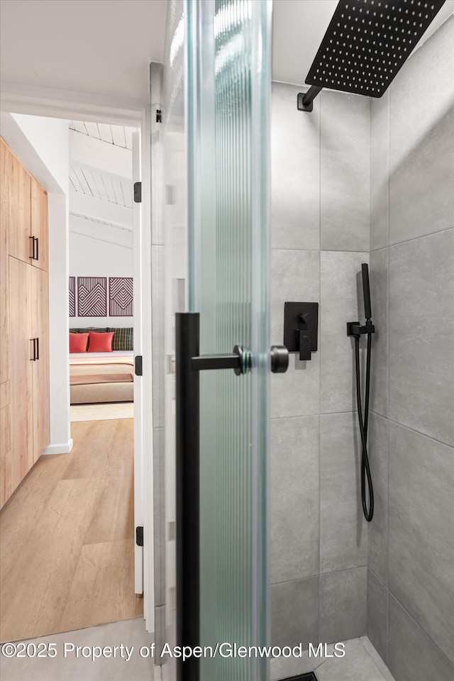 bathroom with a tile shower and hardwood / wood-style floors