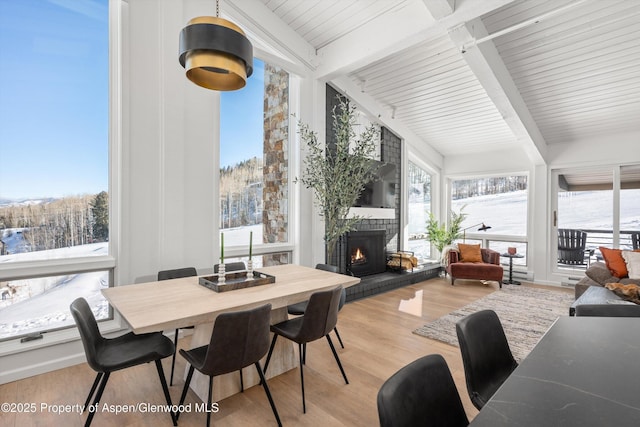 sunroom / solarium with a fireplace, vaulted ceiling with beams, and a healthy amount of sunlight