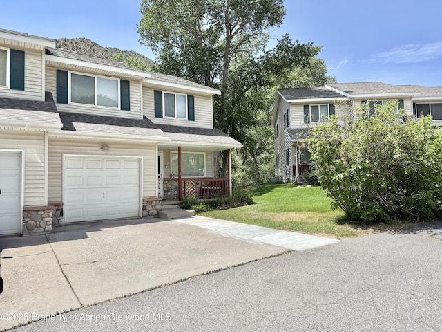 289 Mikala Ln, New Castle, CO 81647 - townhome / multi-family property featuring covered porch, concrete driveway, an attached garage, stone siding, and a front lawn