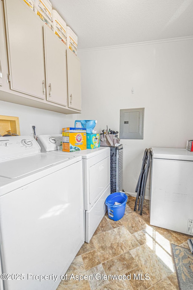 laundry room featuring cabinet space, washer and clothes dryer, electric panel, crown molding, and stone finish floor
