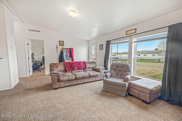 carpeted living area with visible vents, a textured ceiling, and vaulted ceiling