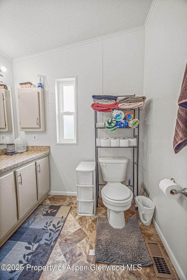 bathroom with ornamental molding, toilet, vanity, visible vents, and a textured ceiling