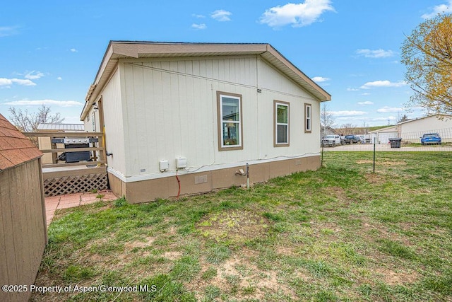 view of side of property with fence, a wooden deck, a yard, and crawl space