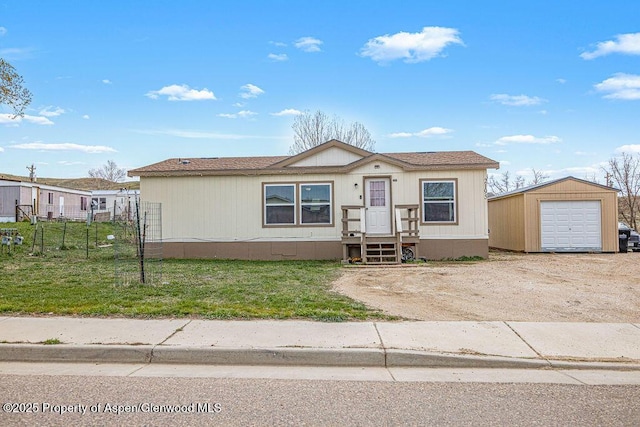 manufactured / mobile home featuring a front yard, a garage, an outbuilding, driveway, and fence