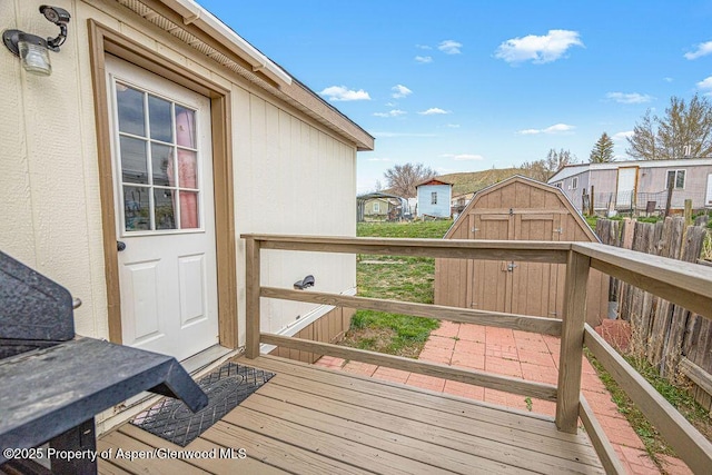 wooden deck with an outdoor structure, a shed, and fence