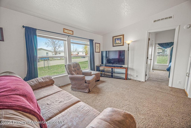 carpeted living room featuring visible vents, a textured ceiling, and vaulted ceiling