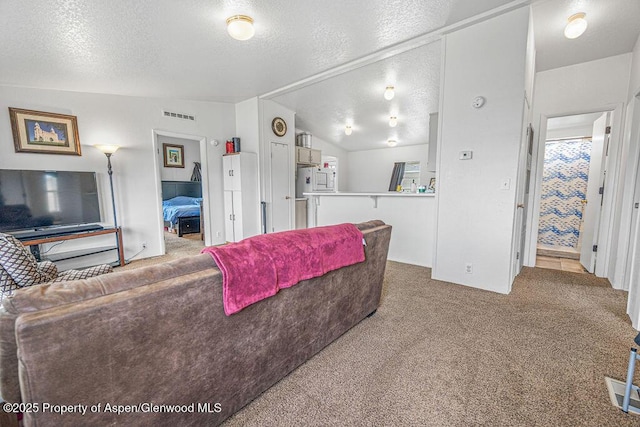 living room with visible vents, a textured ceiling, and carpet