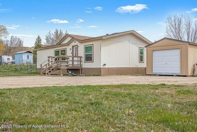 manufactured / mobile home featuring an outbuilding, a front lawn, a wooden deck, and a garage