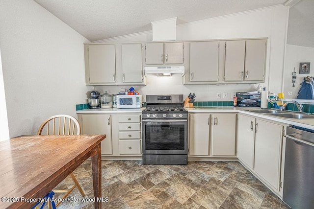 kitchen with stainless steel appliances, under cabinet range hood, stone finish flooring, light countertops, and lofted ceiling