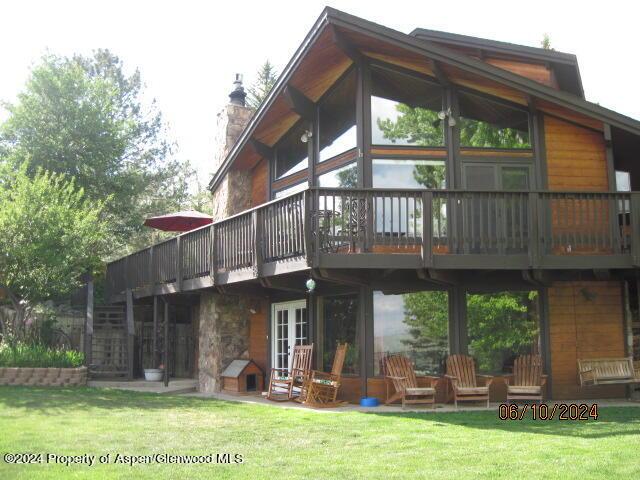 rear view of property with a chimney, a deck, and a yard