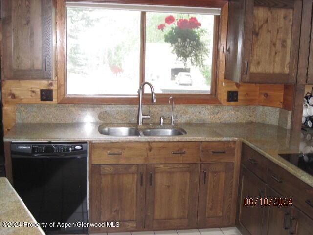 kitchen featuring black appliances, brown cabinetry, a sink, and light countertops