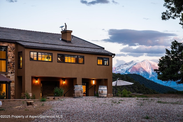 1108 County Road 110, Glenwood Springs, CO 81601 - view of front facade featuring a mountain view, a chimney, stucco siding, stone siding, and a tiled roof