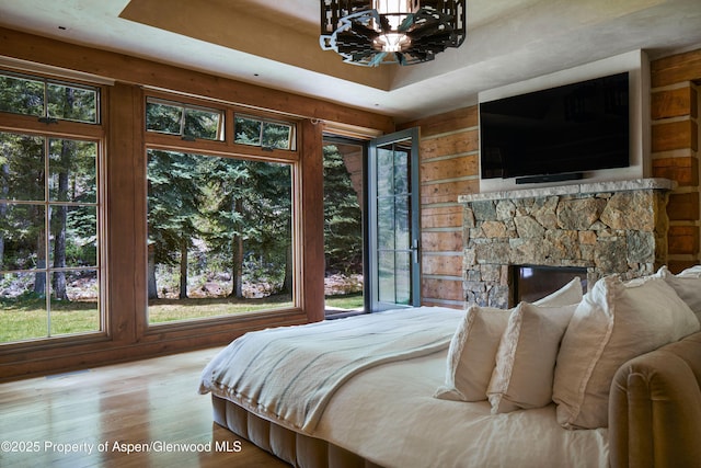143 N Conundrum Creek Rd, Aspen, CO 81611 - bedroom with a chandelier, multiple windows, wooden walls, wood finished floors, and a stone fireplace